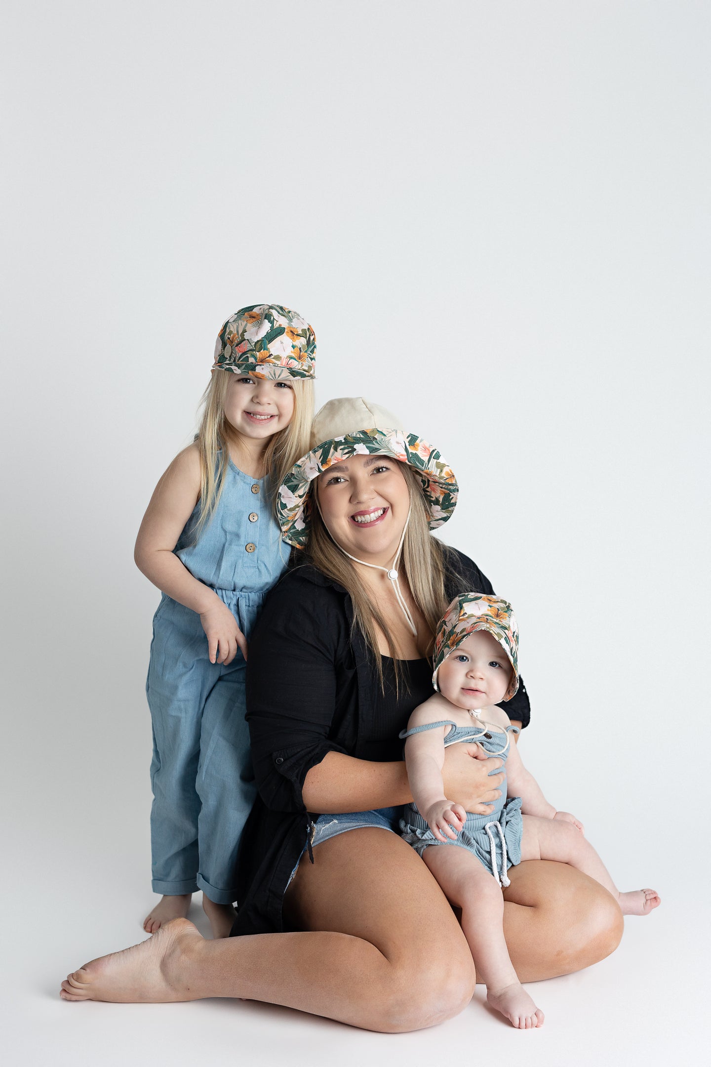 Mother, baby boy, and baby girl wearing Newbornlander's Summer Hat, Summer Baseball Cap, and Summer Bonnet with happy smile