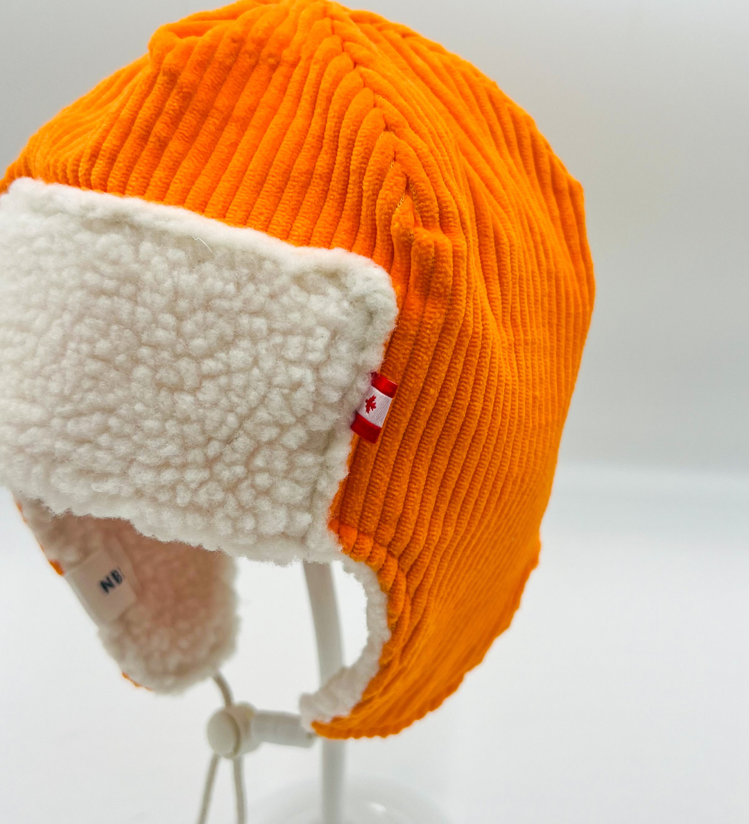 Bright orange corduroy baby pilot hat with sherpa lining and chin strap, side view, Made in Canada