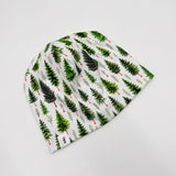 Newbornlander Christmas Pine beanie hat for babies, white cotton with watercolour evergreen trees and red berries, side view