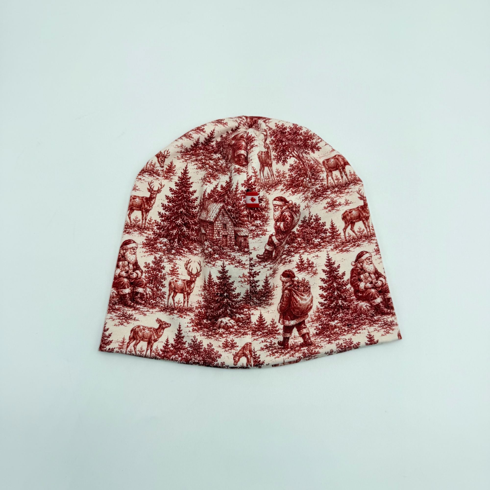 Christmas Scene baby beanie hat with Canadian flag label, red toile Santa and reindeer print, back view
